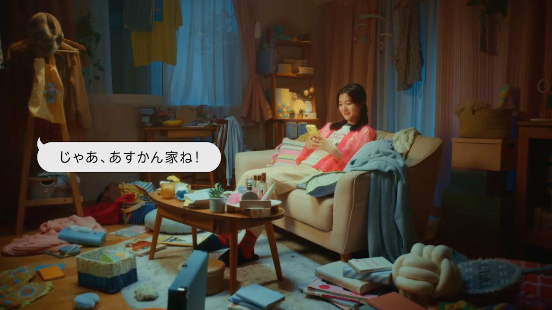 散らかった部屋でスマホを見る女性