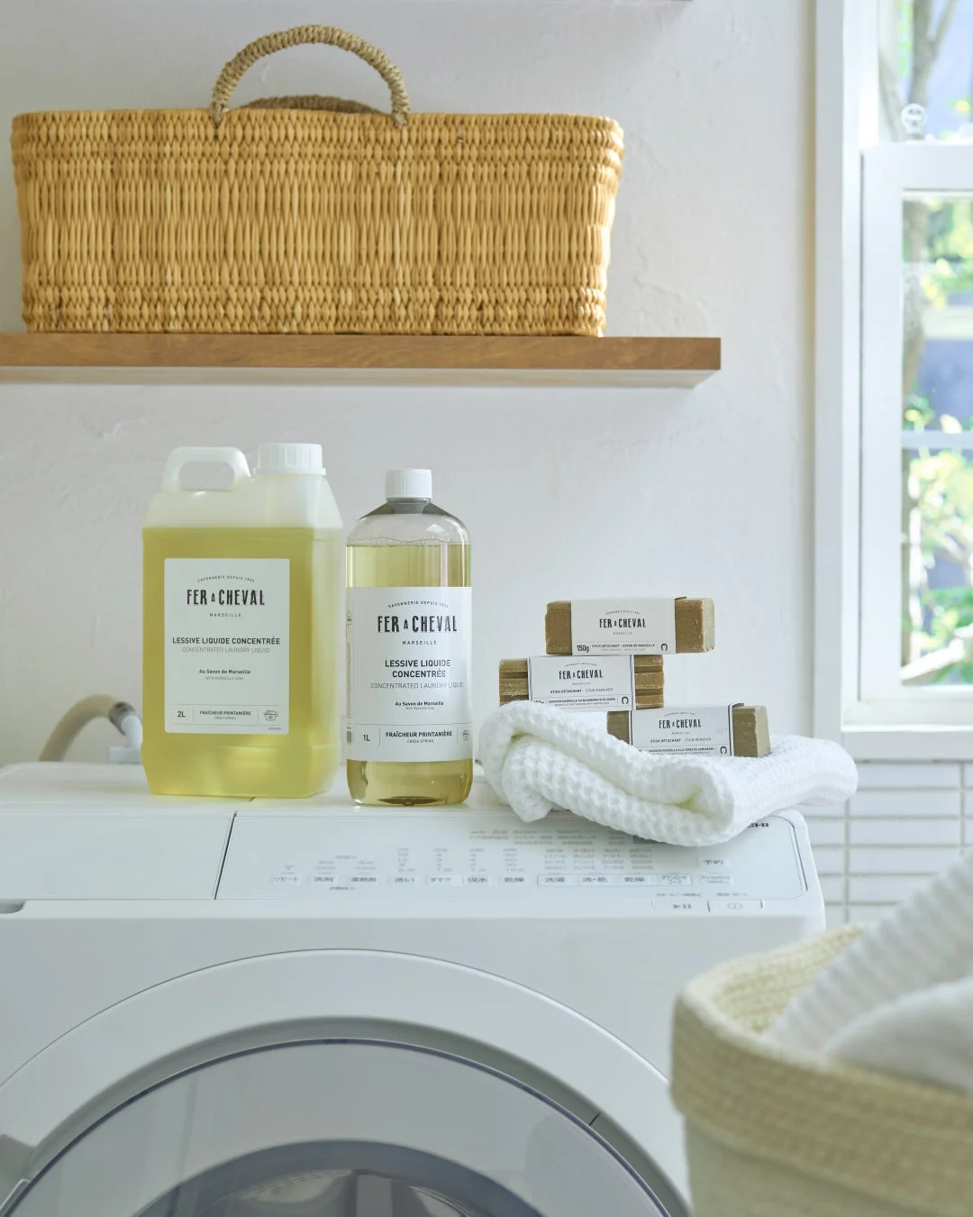 FER À CHEVALの洗濯洗剤とマルセイユ石鹸、白いタオルが並べられた洗濯機の上