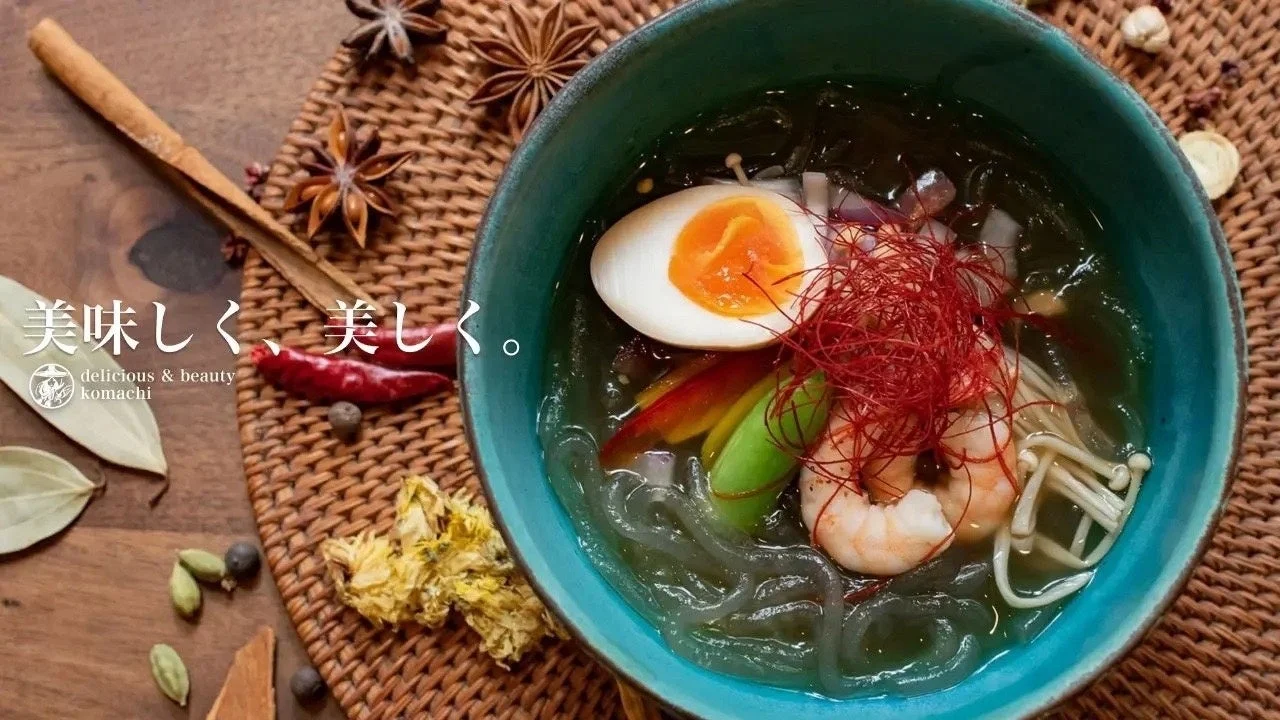 海老や半熟卵、キノコ、野菜などが入った透明なスープの麺料理