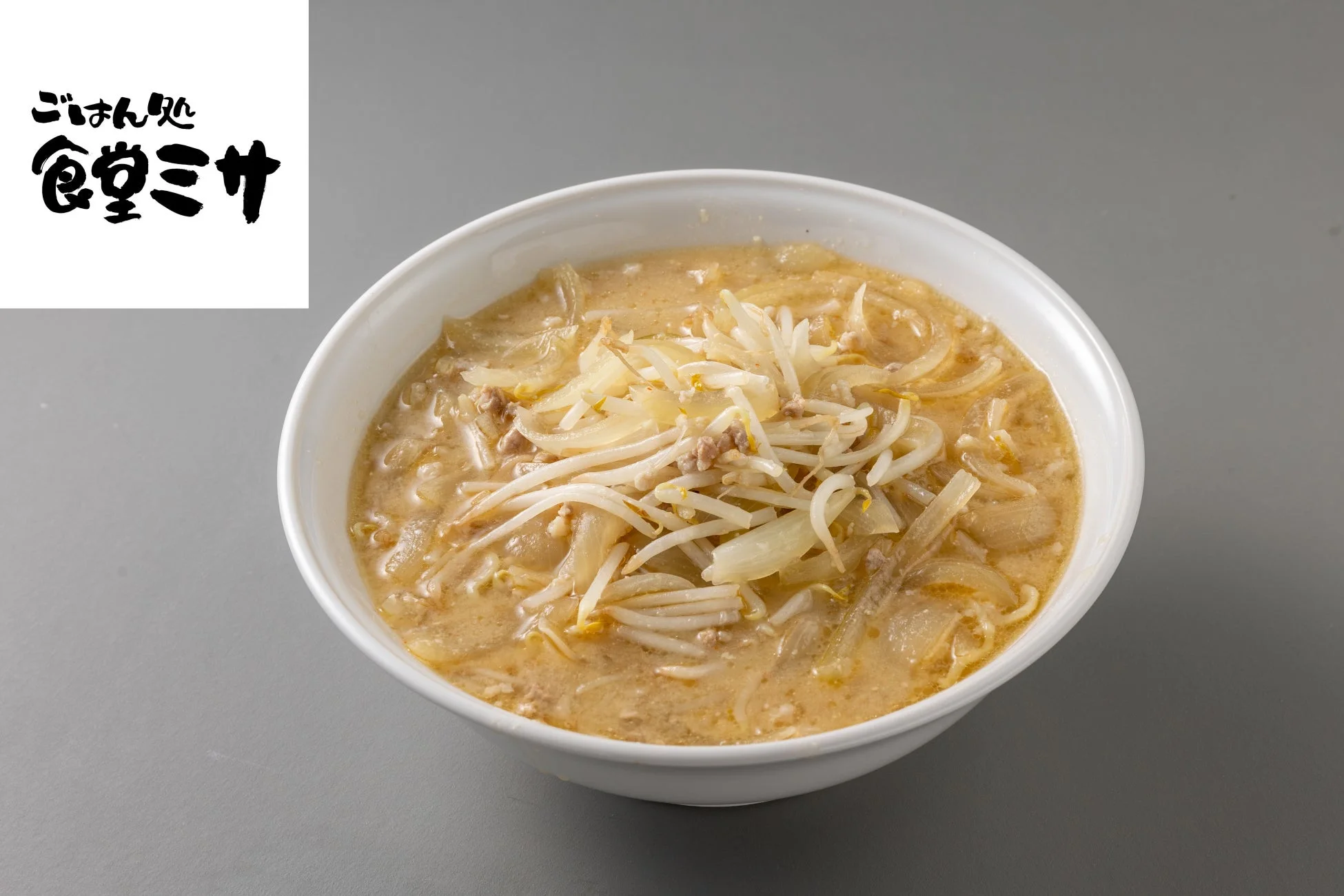 「ごはん処 食堂ミサ」のラーメン。クリーミーなスープに、スライスされた玉ねぎ、もやし、ひき肉がたっぷりと盛り付けられた一品です。温かくて美味しそうな雰囲気が伝わります。