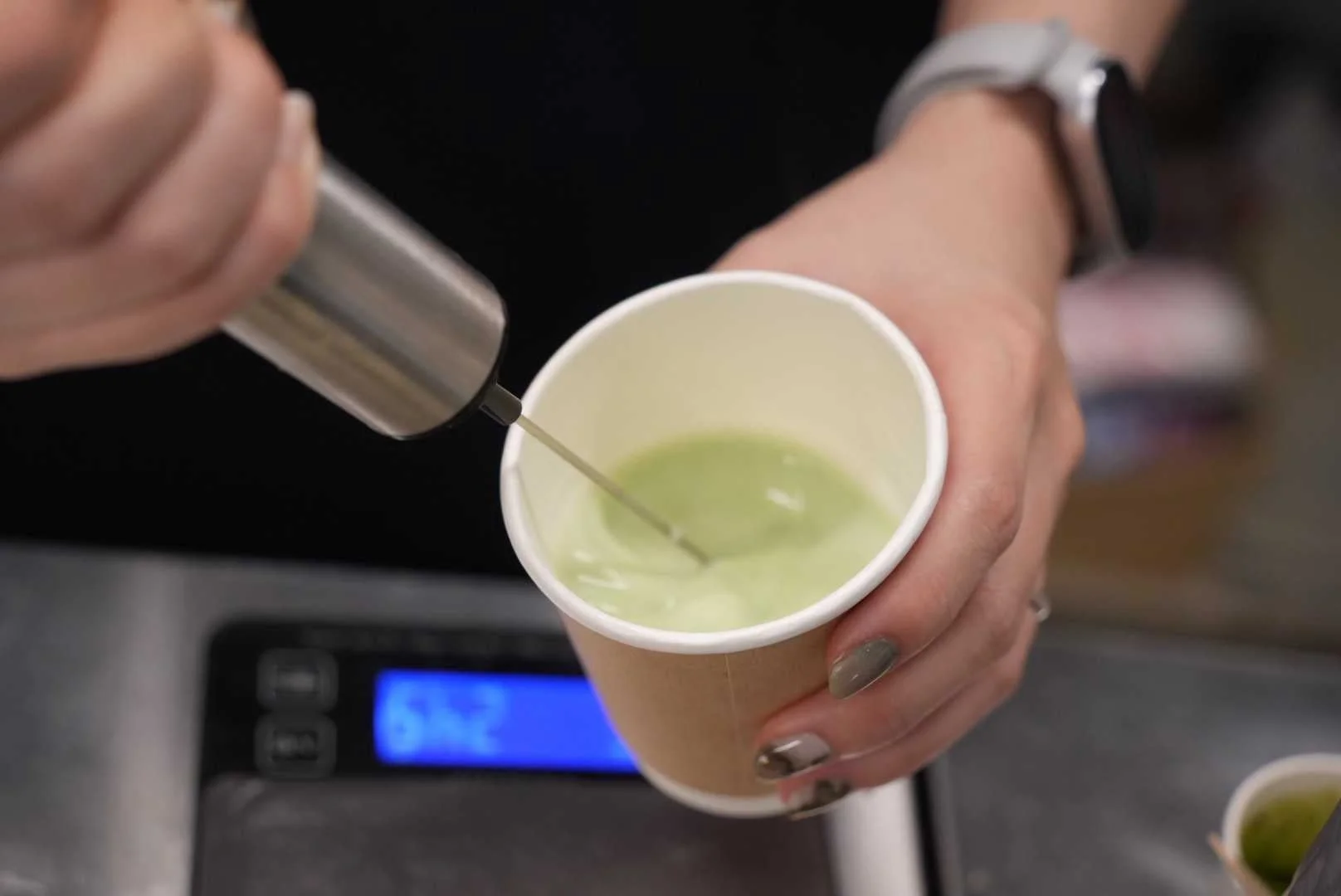 抹茶のような緑色の飲み物を混ぜている様子