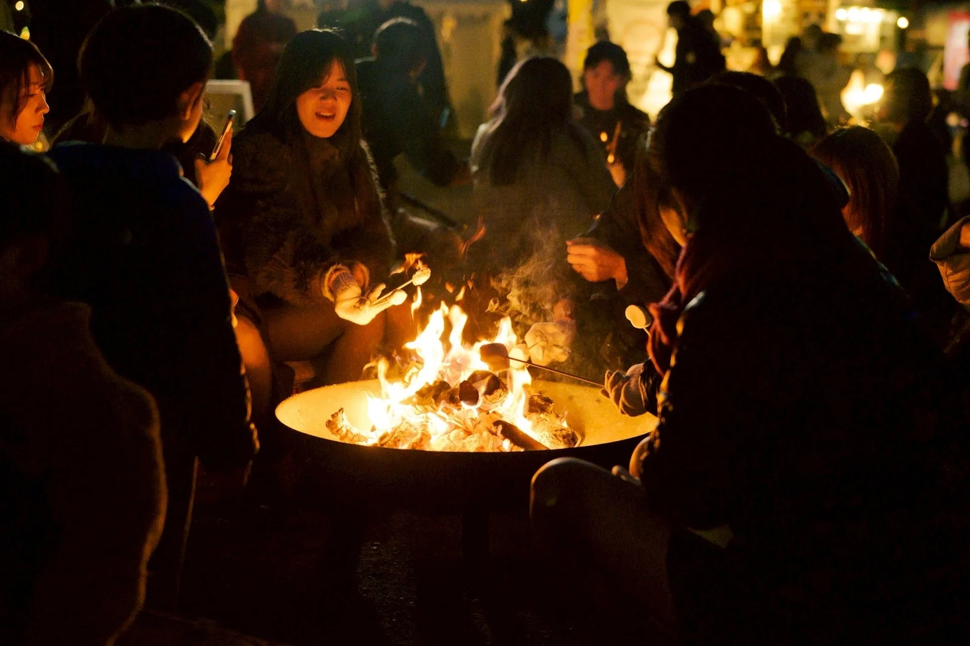 焚き火を囲んでマシュマロを焼く人々