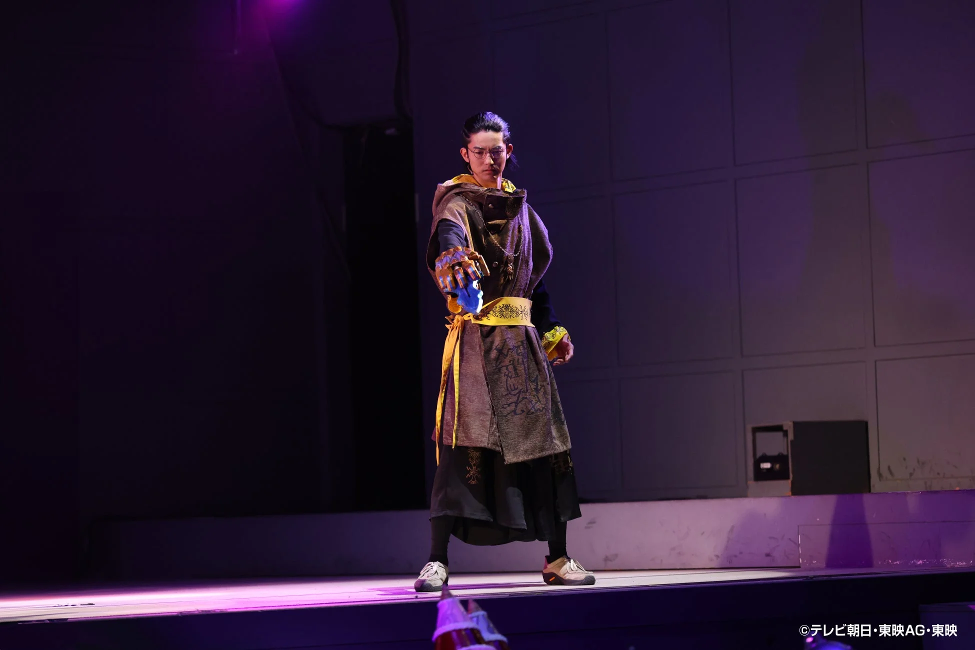 紫の照明が当たる舞台でのアクション
