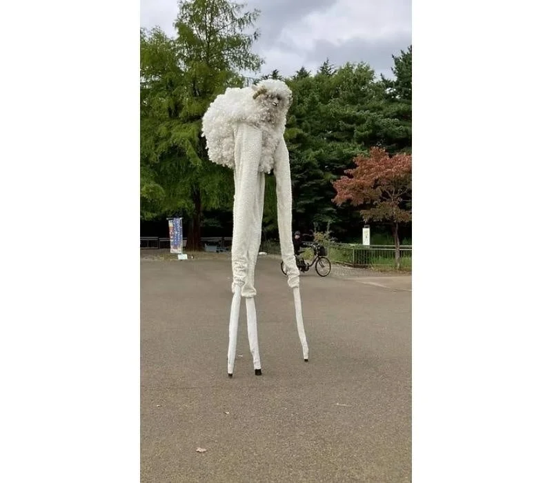 羊のコスチュームで足長ウォーキングをするパフォーマー