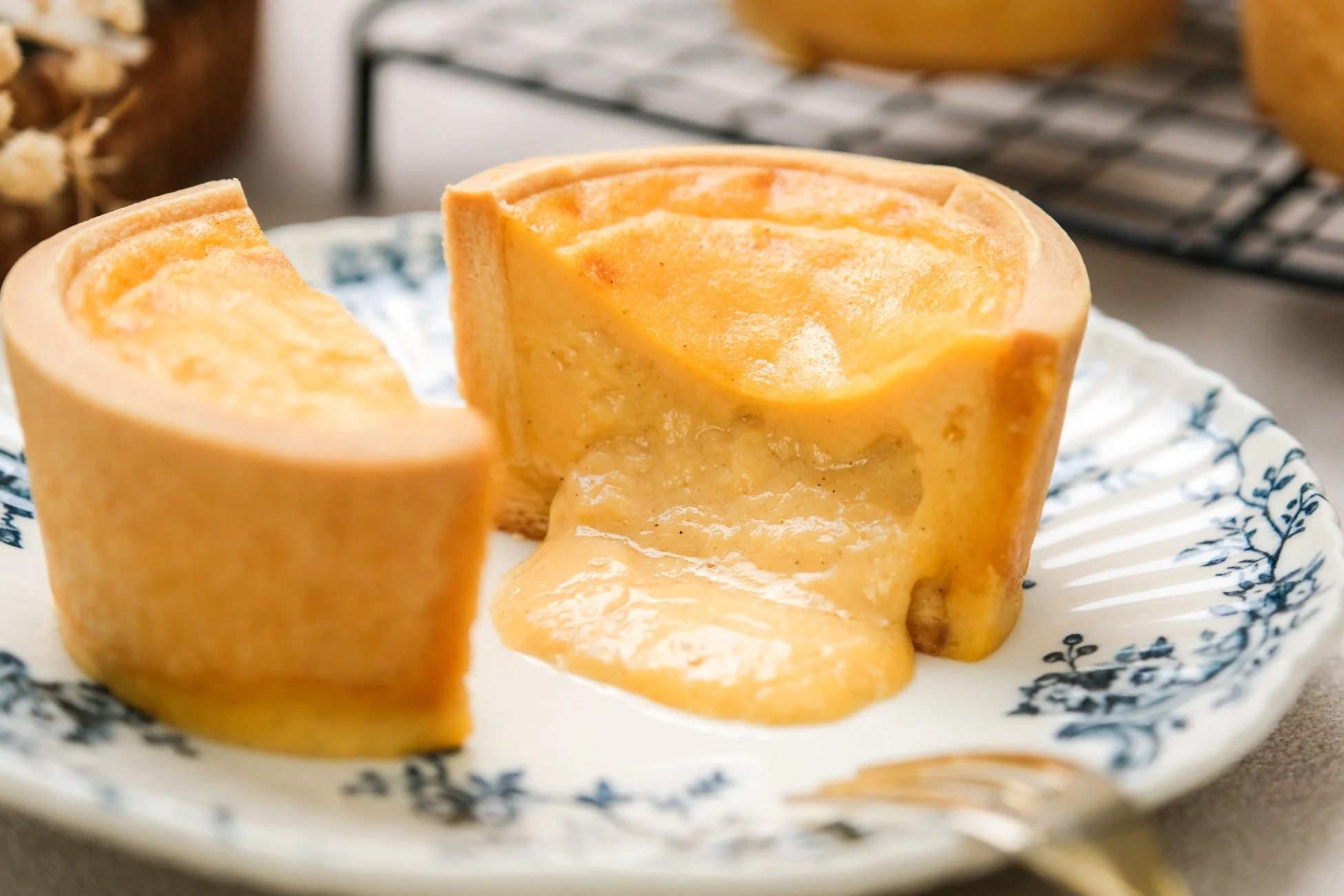 断面からとろけるようなクリームが溢れ出す、美味しそうなチーズタルトが白い花柄の皿に盛られています。