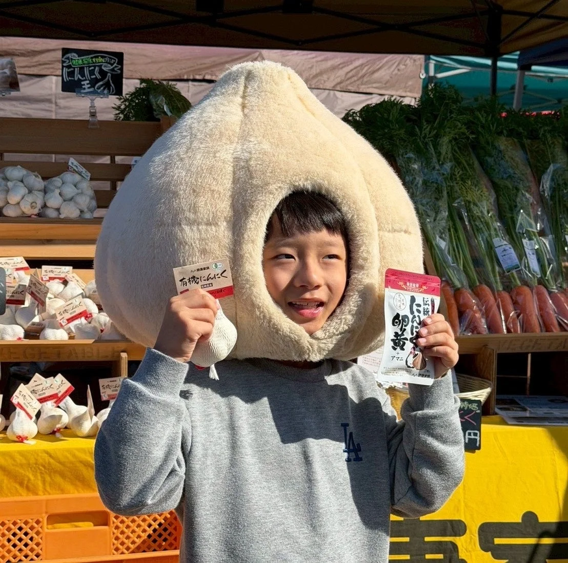 にんにくの着ぐるみを着た子供が笑顔を見せる