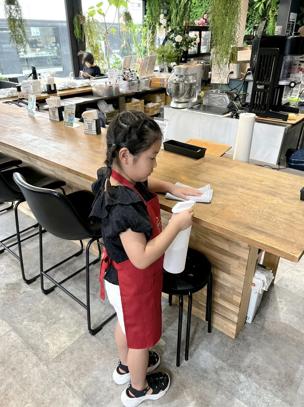 エプロンを着用しカウンターを拭く女の子