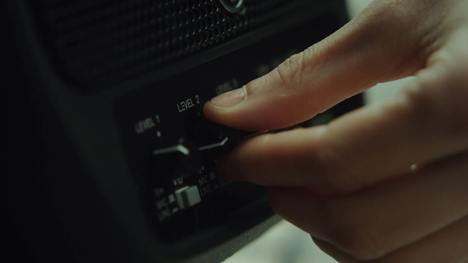 オーディオ機器のレベル調整ノブを操作する手