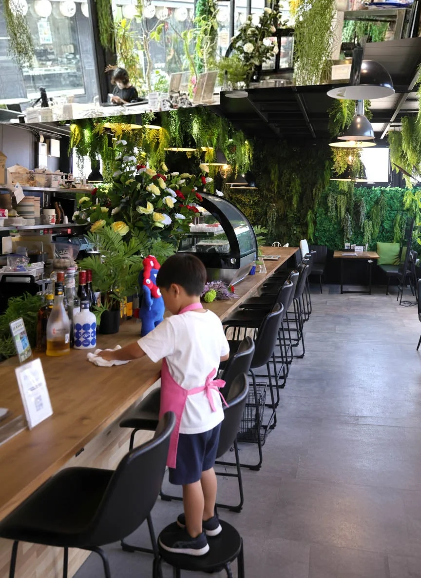 エプロンを着用しカウンターを拭く少年