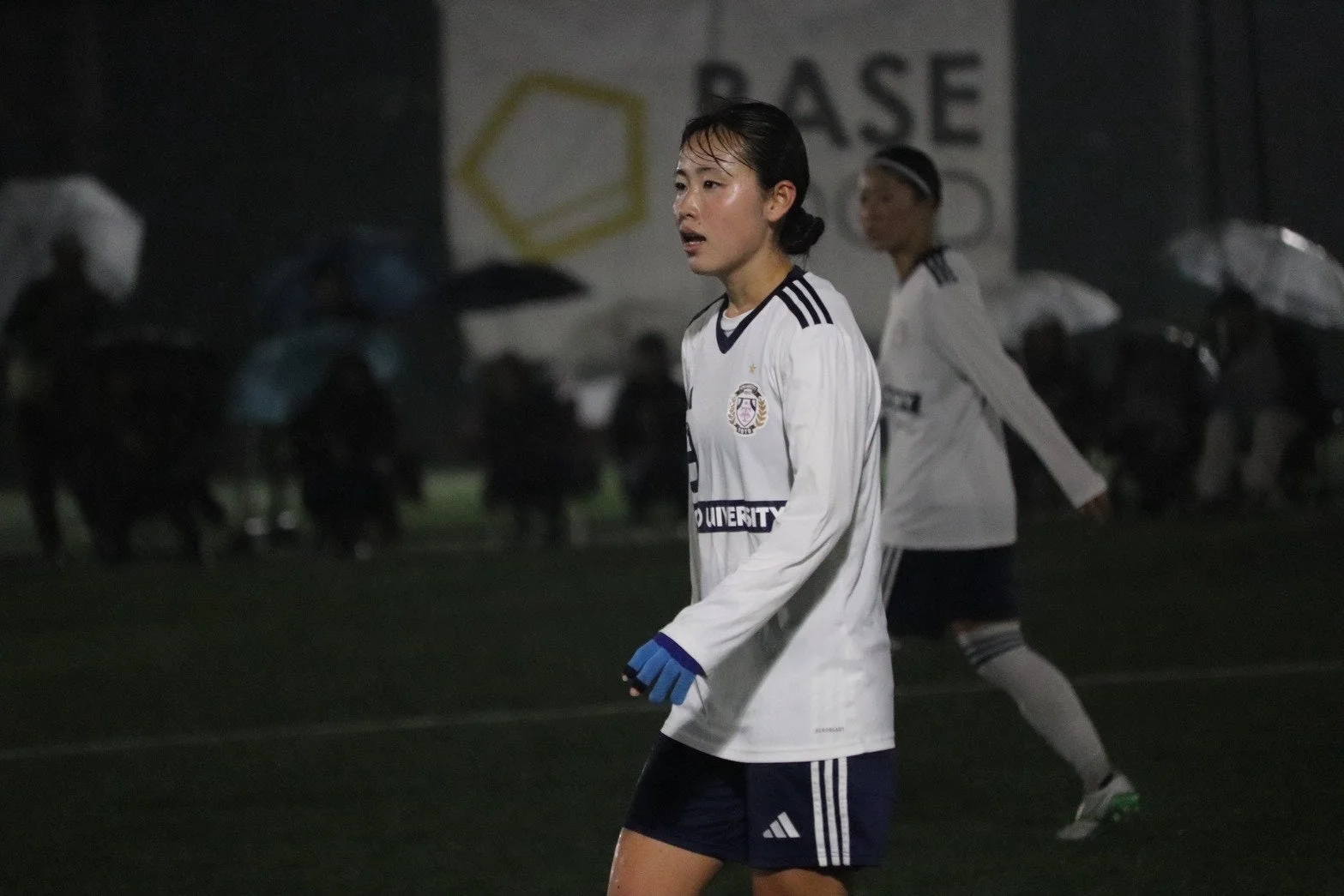 夜のサッカー場でプレーする女子サッカー選手