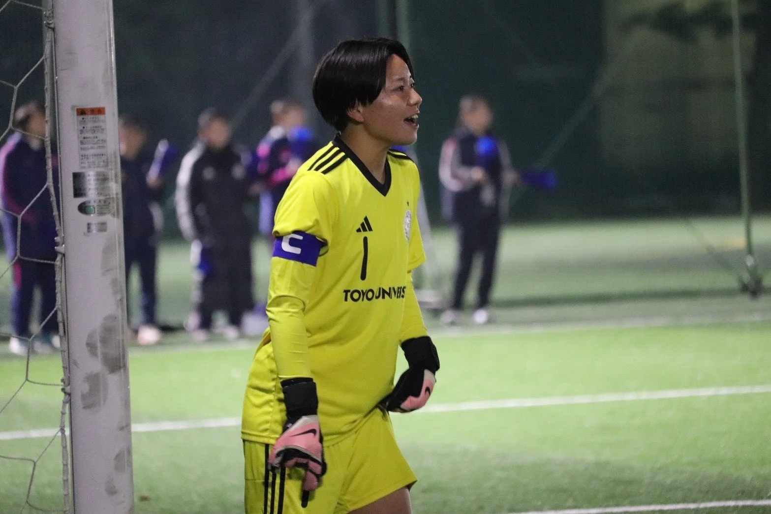 夜のサッカー場で指示を出す女性ゴールキーパー