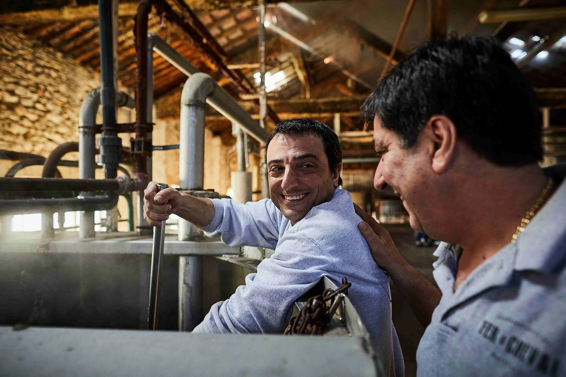 古い工場のような場所で、一人の男性が笑顔で何かをかき混ぜている