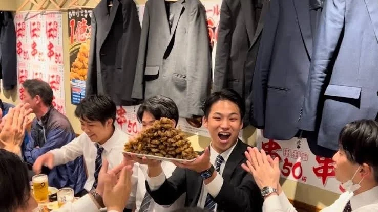 居酒屋で伝串を囲んで盛り上がる客