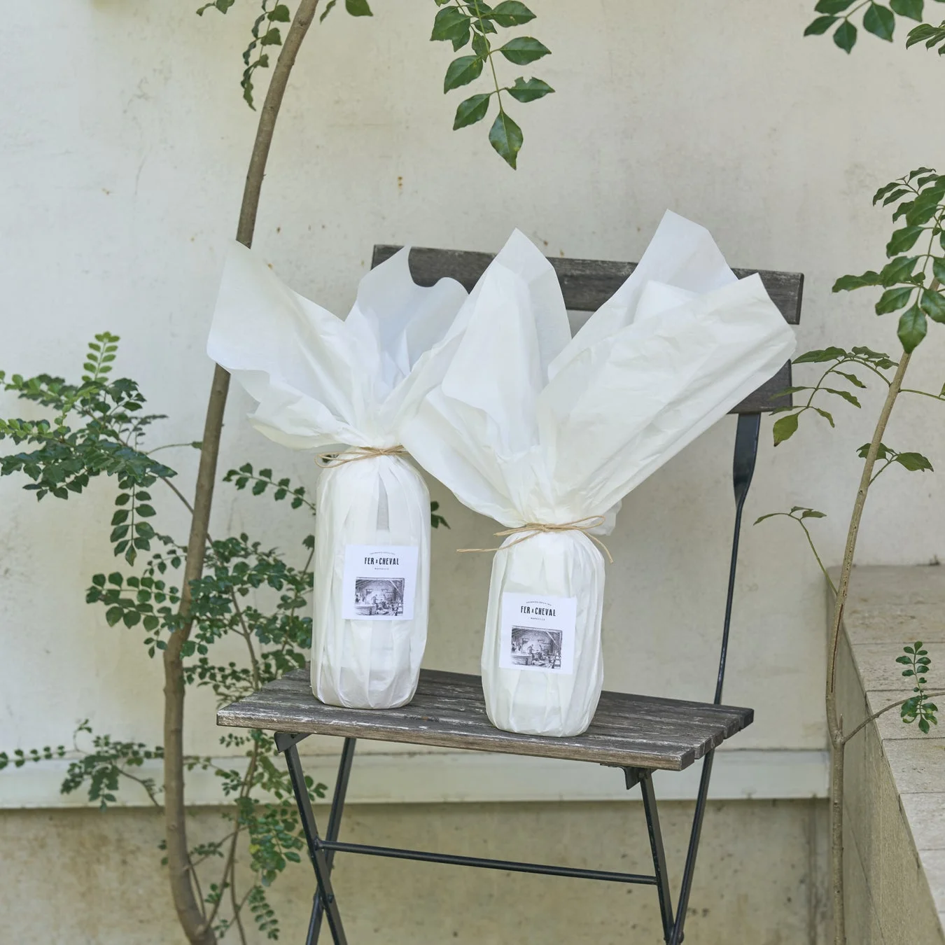 FER+CHEVALのボトルが木製の折りたたみ椅子に置かれ、ナチュラルで落ち着いた雰囲気のギフトシーン