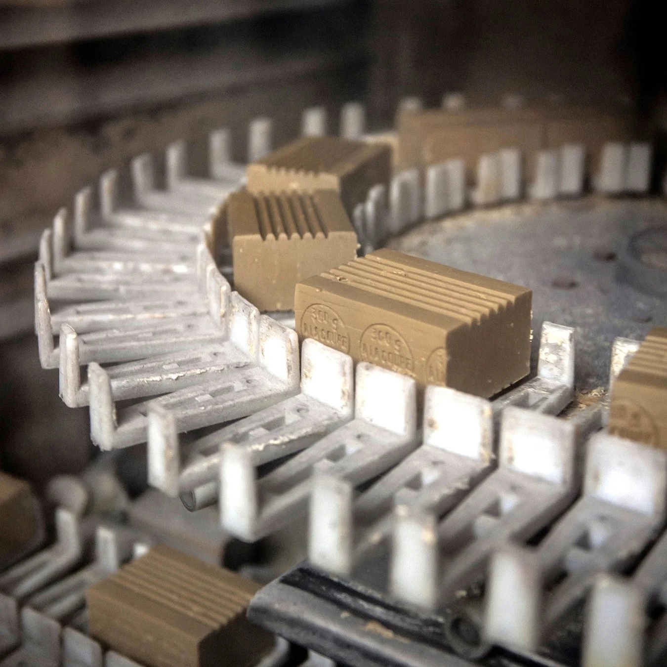 茶色い固形石鹸が製造ラインのコンベアベルト上を流れていく様子