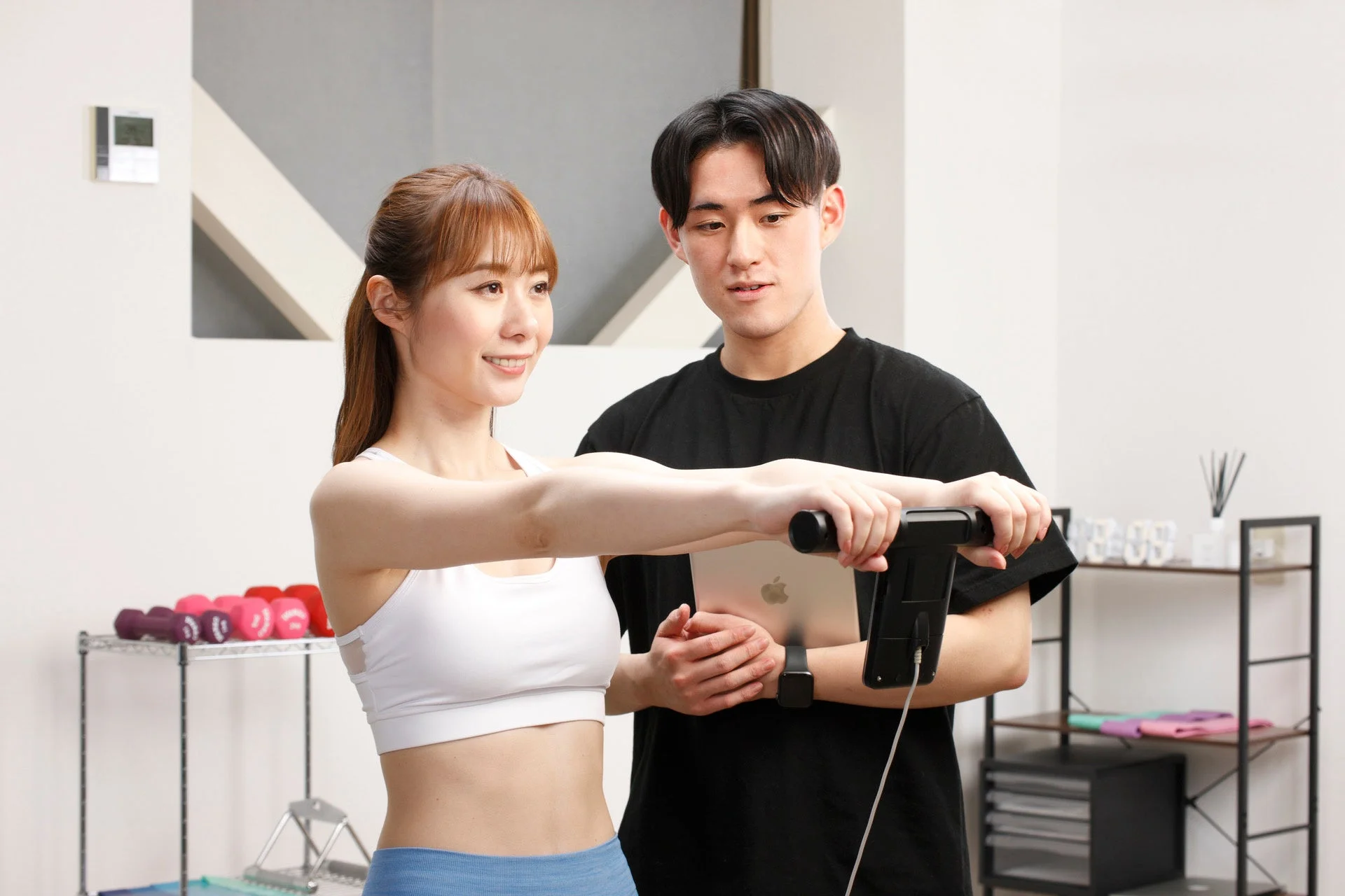 体組成計で測定する女性とトレーナー