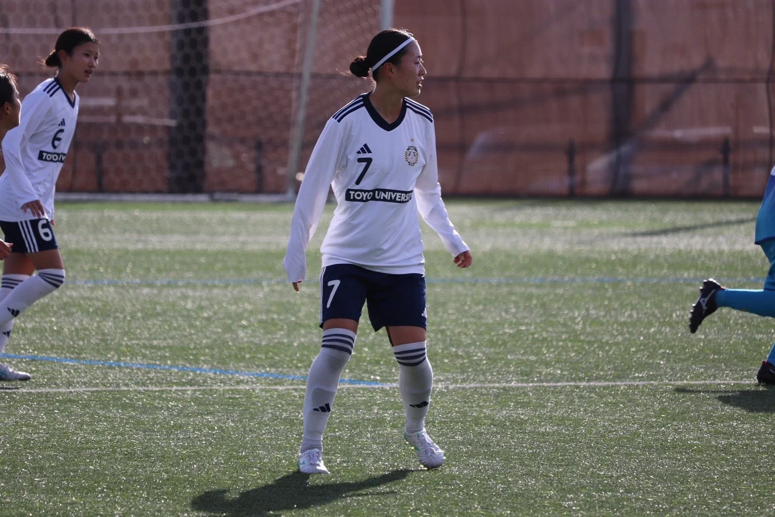 白いユニフォームを着た女性サッカー選手