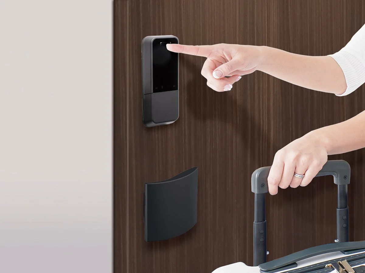 スマートロックに指をかざし、同時にスーツケースのハンドルを握っている人物