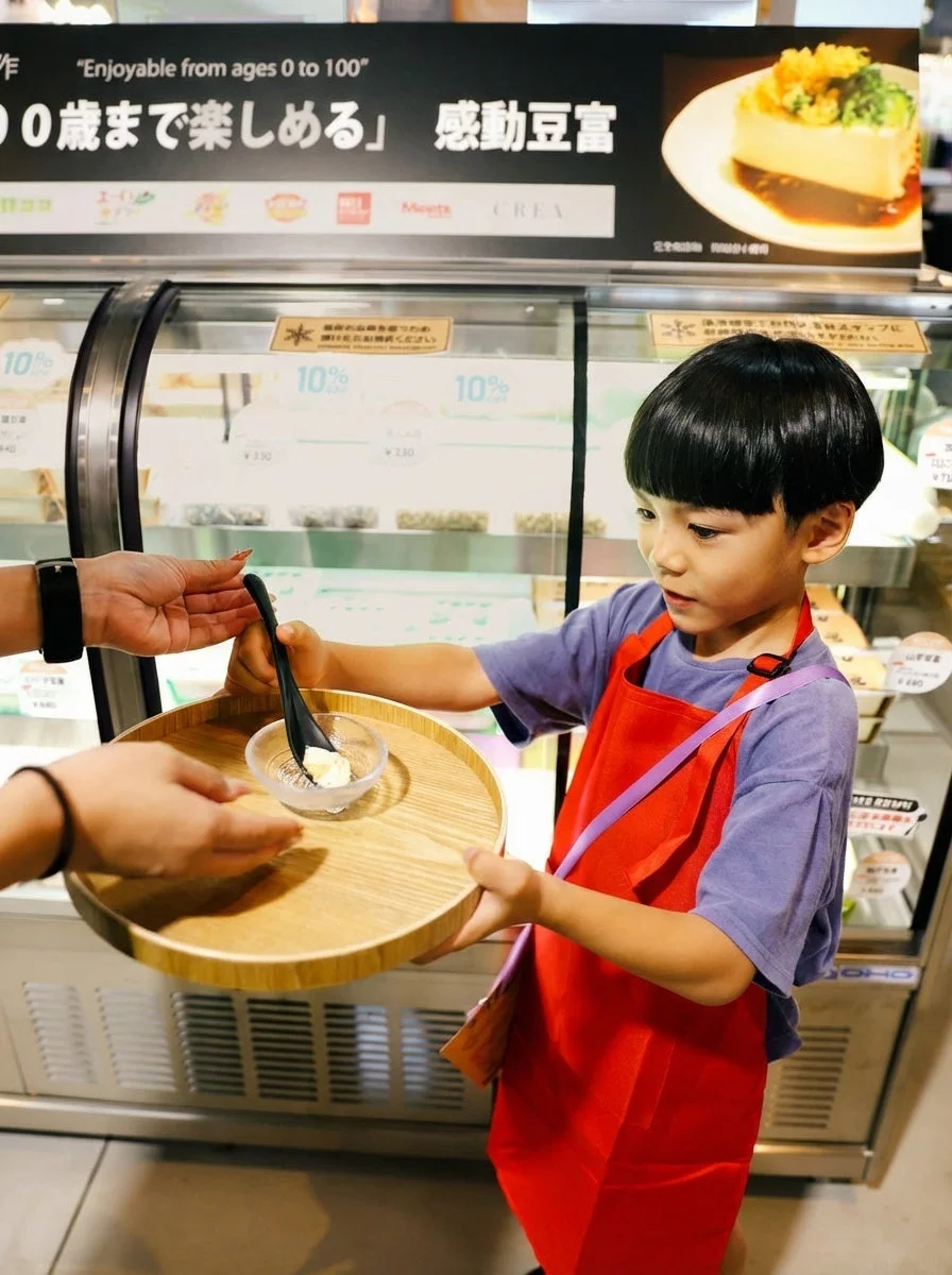 エプロンを着用し試食を受け取る子ども