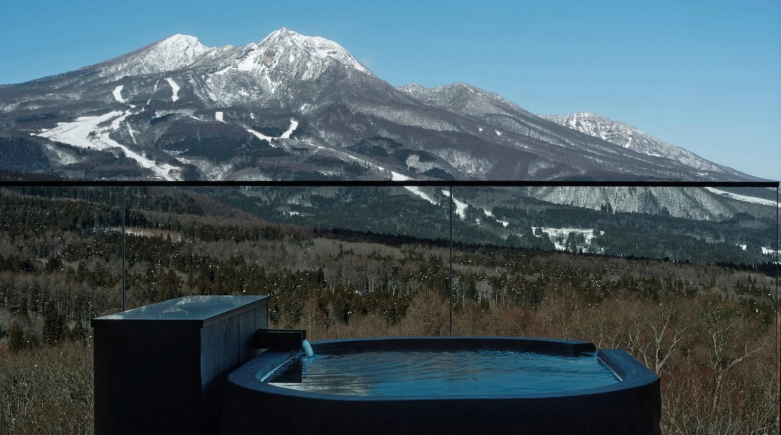 雪化粧した雄大な山々を背景にした露天風呂