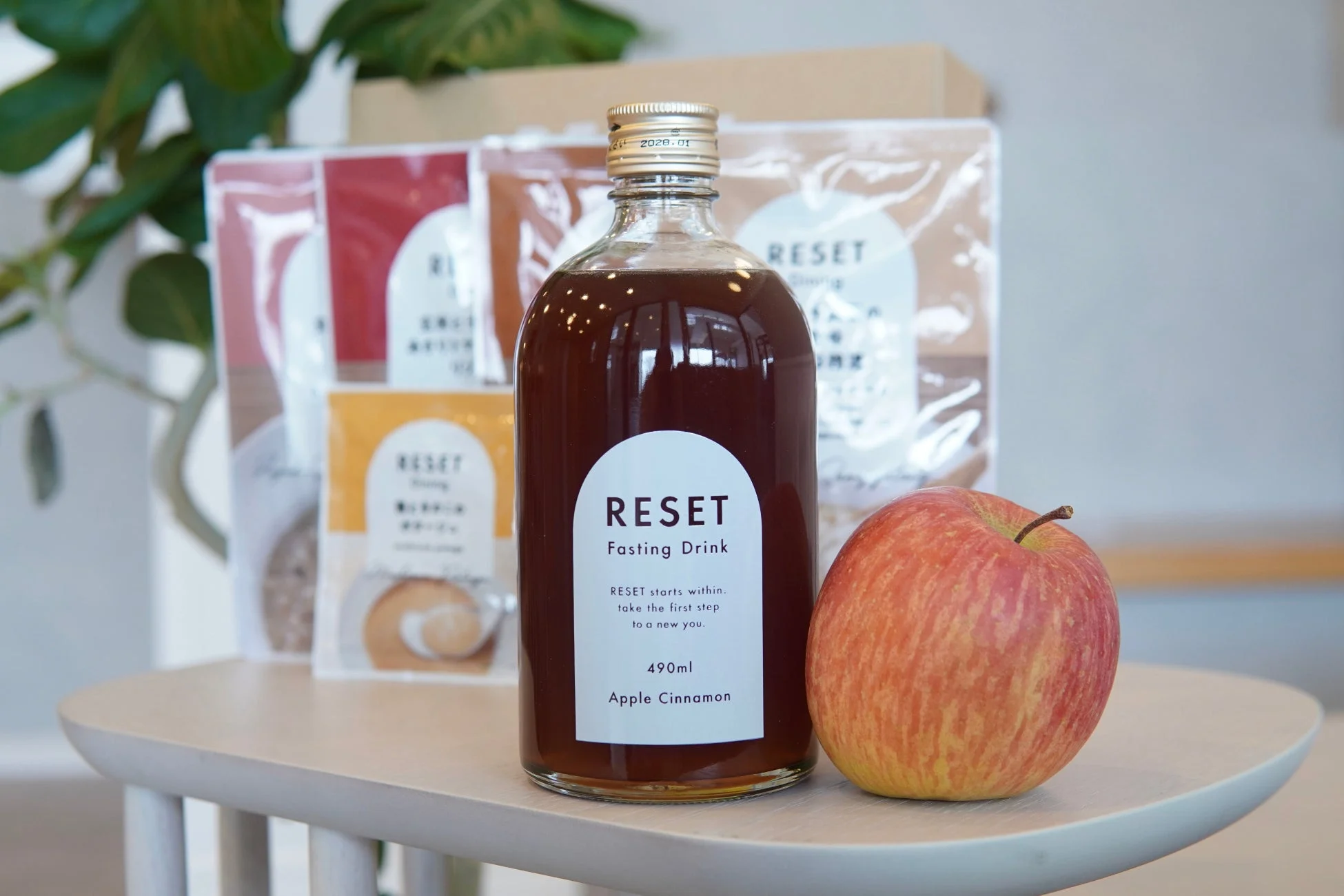 RESETのアップルシナモン味ファスティングドリンクボトルと新鮮なリンゴ