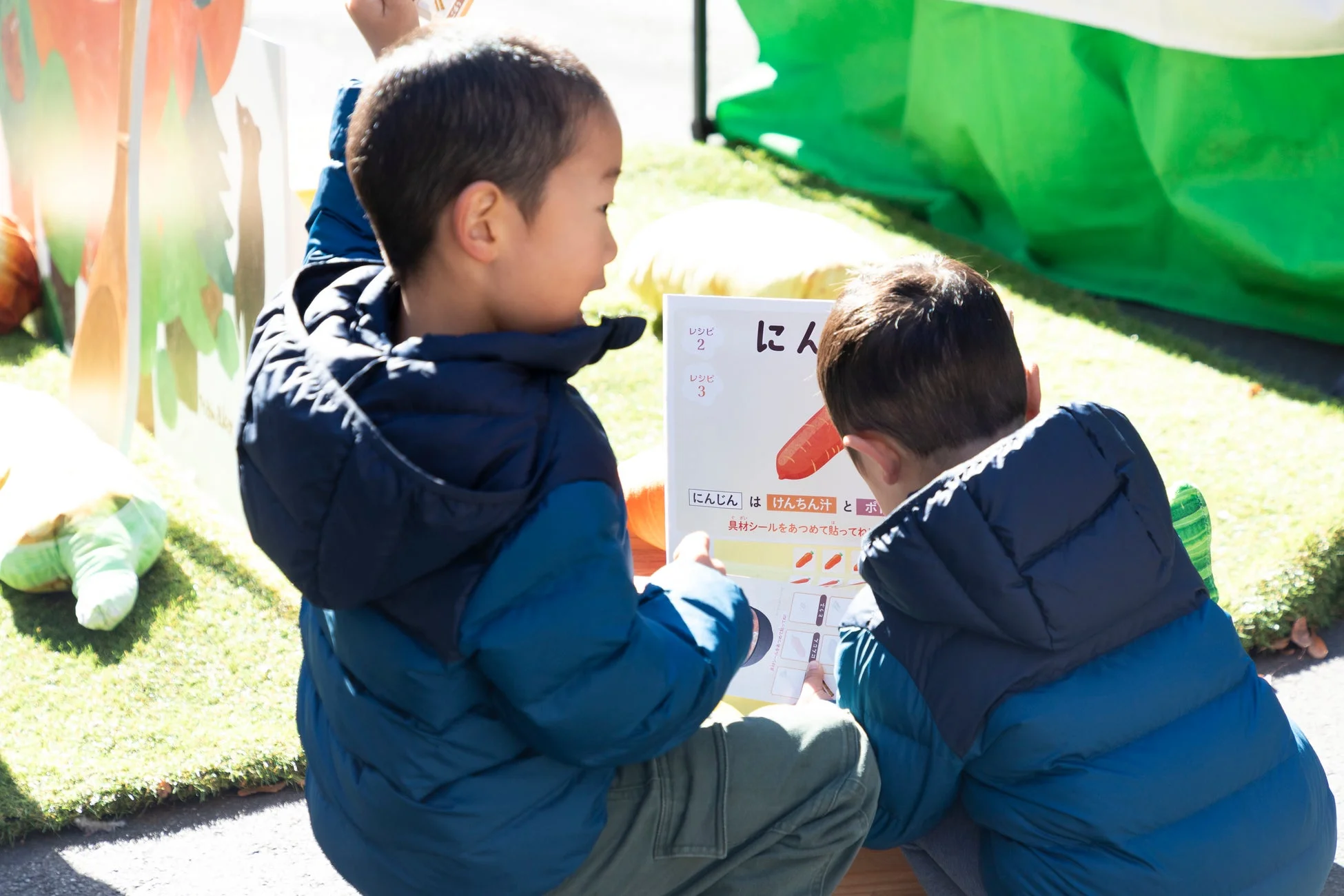 屋外でレシピが書かれたボードを見ている男の子たち