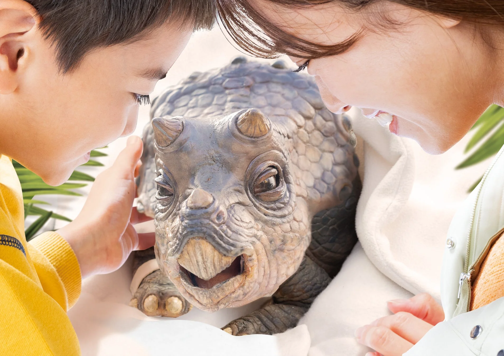 少年と女性が小さな赤ちゃん恐竜を覗き込んでいる様子