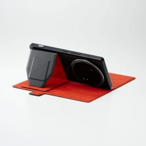 大きなカメラモジュールを持つ黒いスマートフォンが、内側が鮮やかな赤色の保護ケースで立てられた状態のプロダクト写真