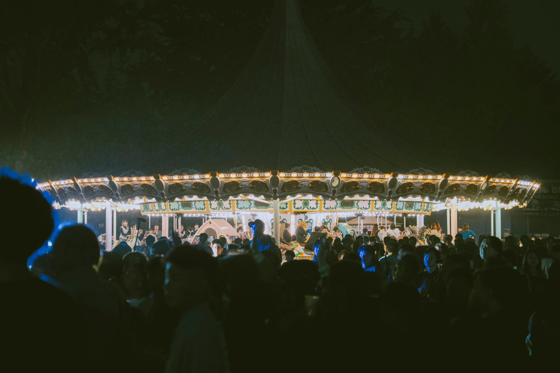 夜の遊園地を彩るメリーゴーランドと賑わう人々