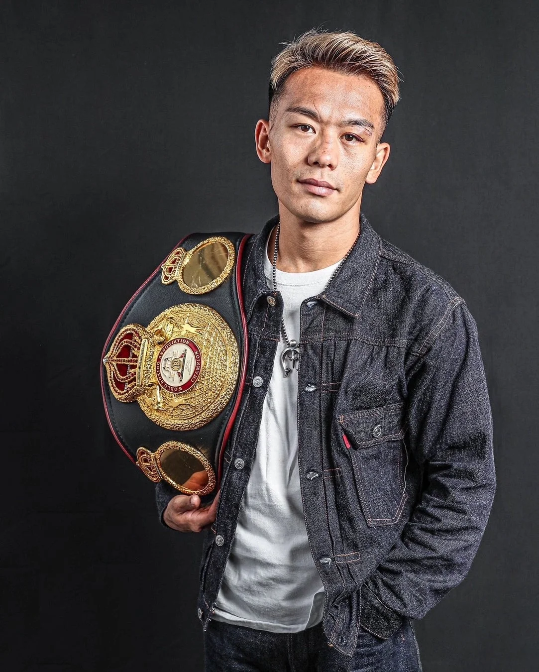 デニムジャケットを着用し、チャンピオンベルトを肩にかけた堤聖也選手