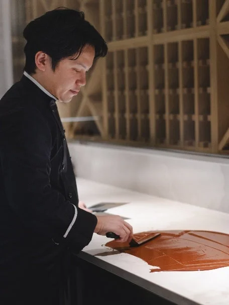 黒いコック服を着た男性が菓子作りに取り組む