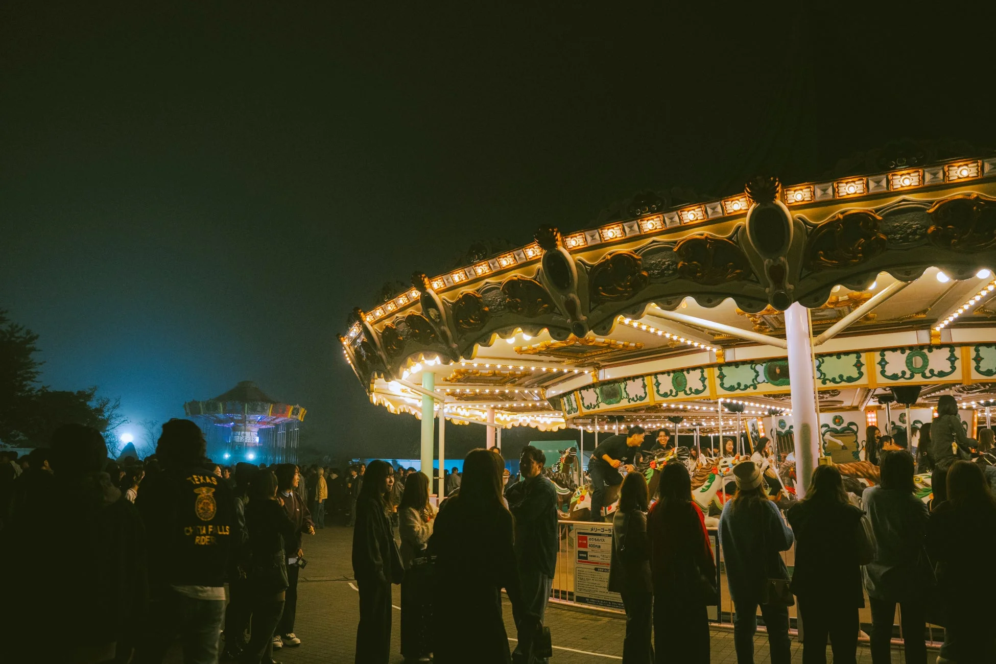夜の遊園地でライトアップされたメリーゴーランドと人々