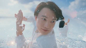 白い服を着た男性が、水しぶきの中でパフォーマンスをしている