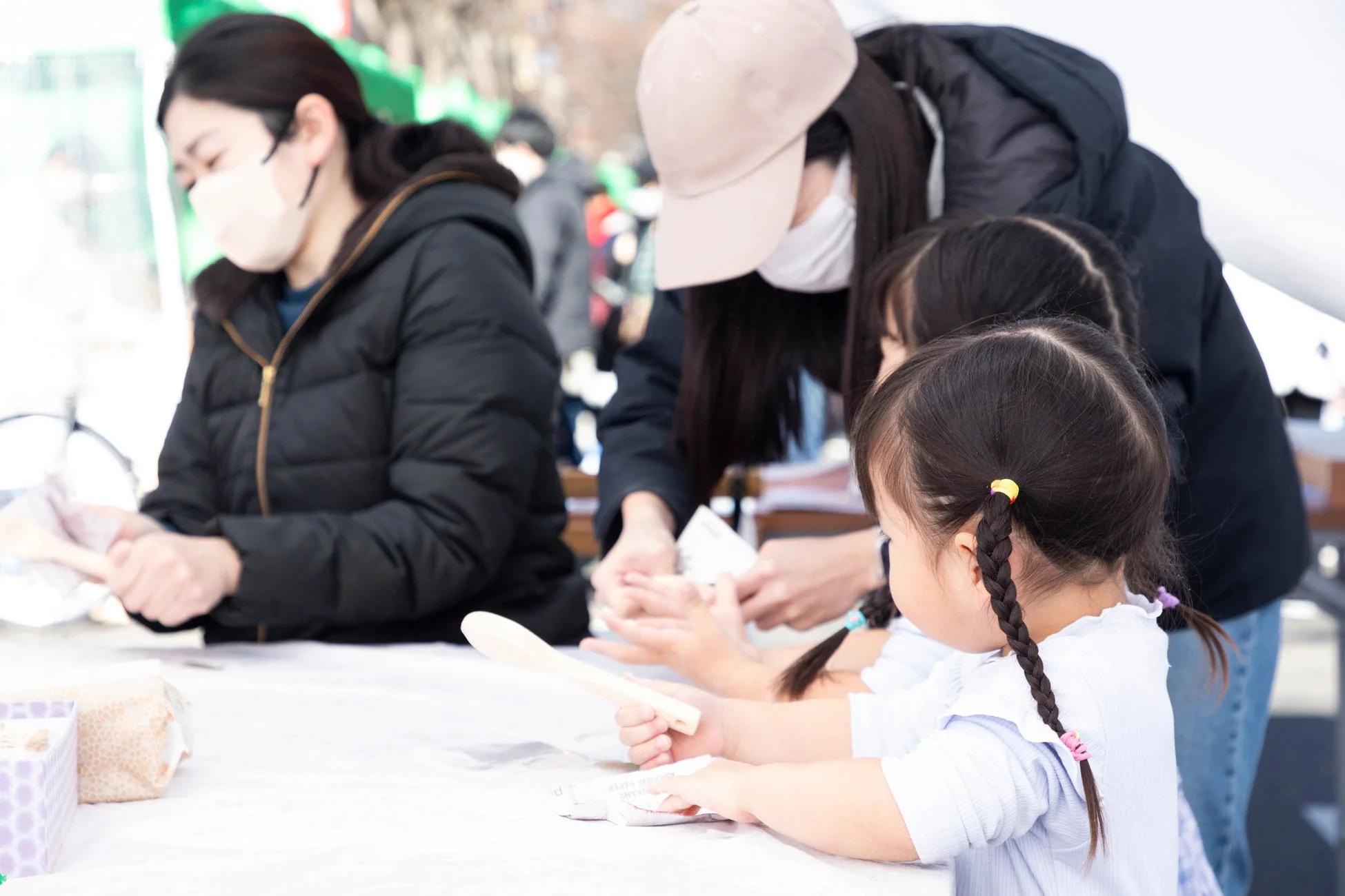 屋外ワークショップで何かに集中して取り組む大人と子どもたち