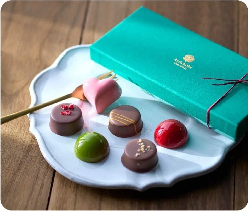 白いおしゃれな皿に、ハート型や様々な色と形のボンボンショコラが美しく並べられています