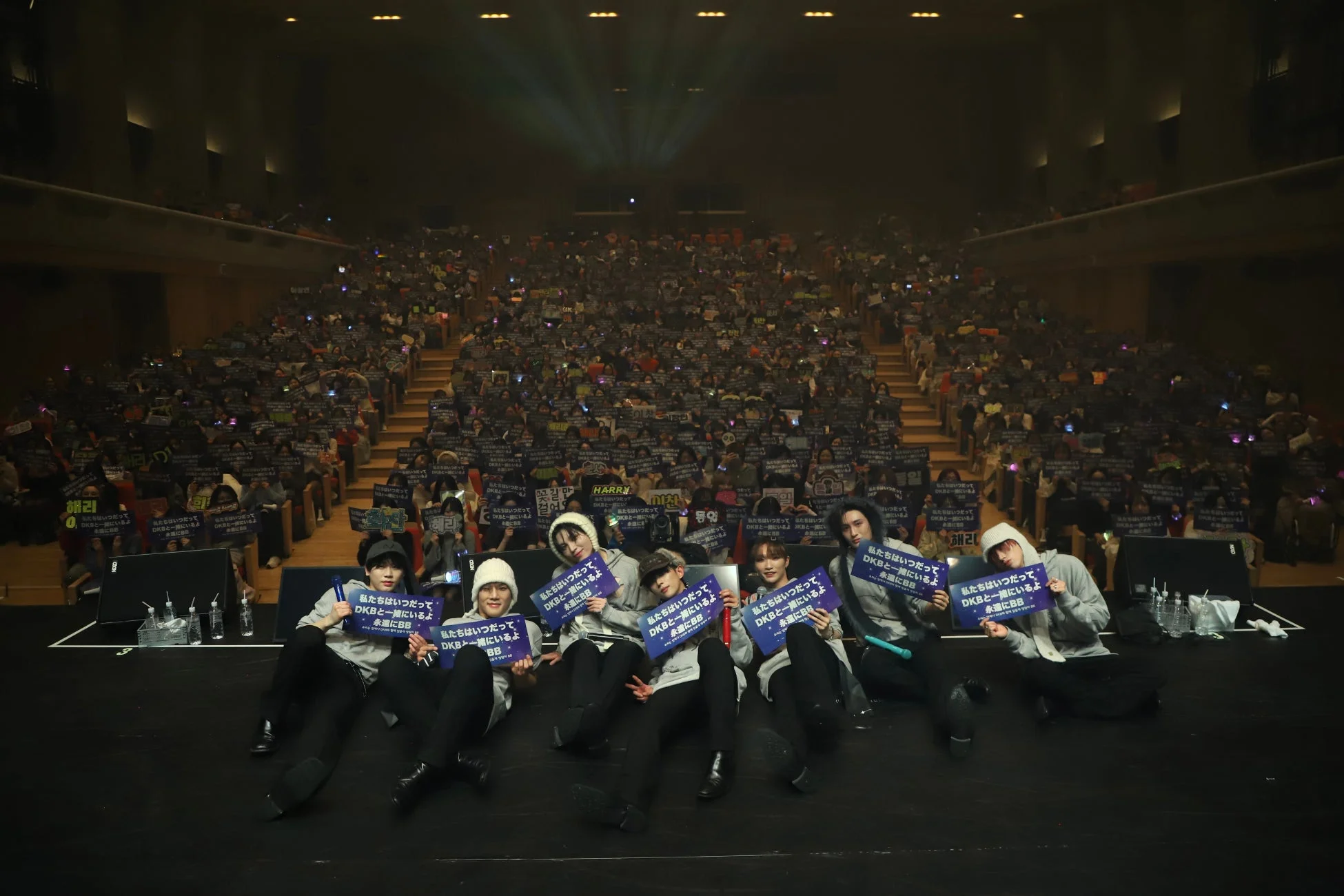 DKBのメンバーがファンに向けてメッセージが書かれたボードを掲げている様子
