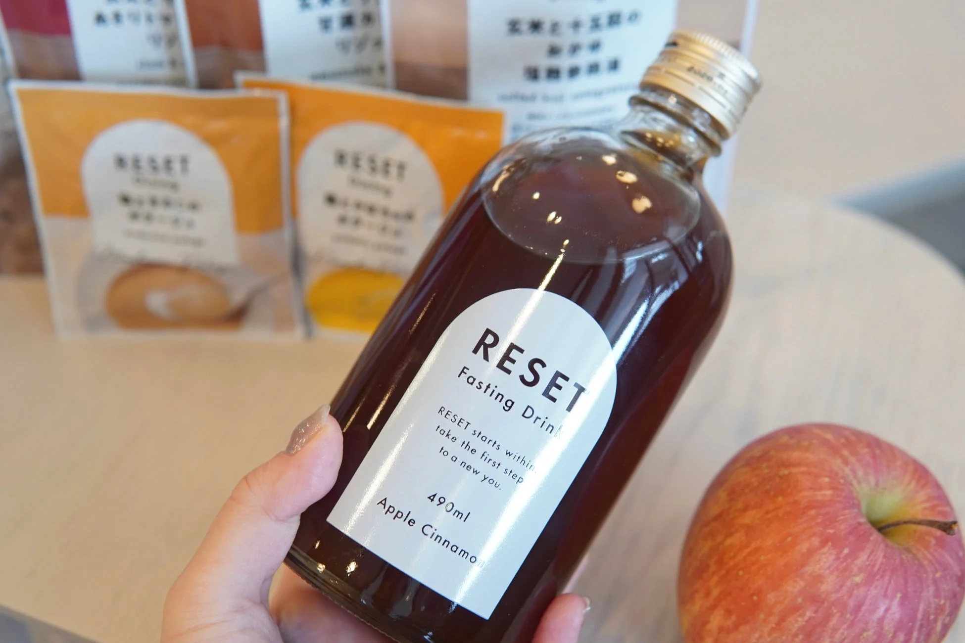 女性がRESET Fasting Drink Apple Cinnamonのボトルを持つ様子