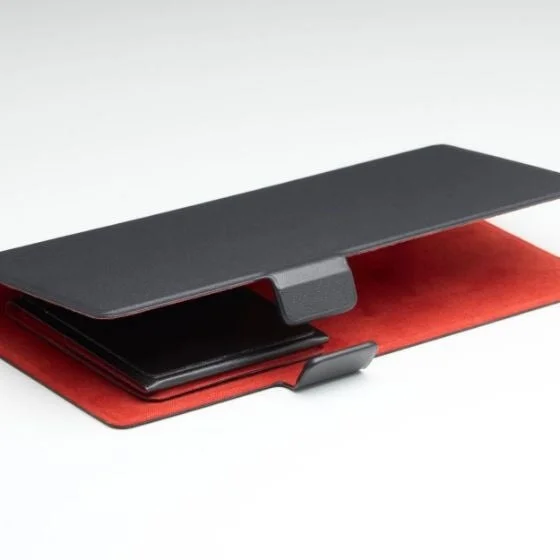 白い背景に置かれた、黒い外装と赤い内装を持つスマートフォンまたはタブレット用保護ケースのクローズアップ