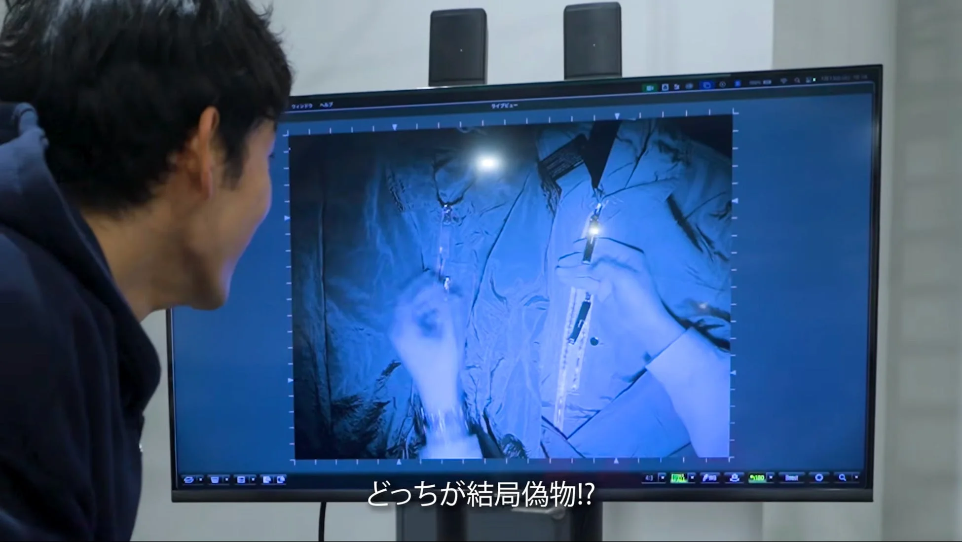 モニターで鑑定結果を確認する男性