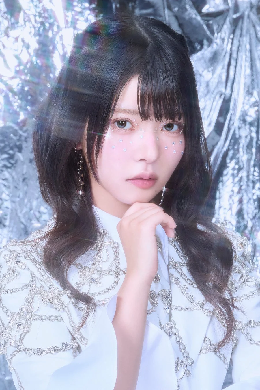 白い装飾的な衣装を着用し、目元にはグリッターメイクを施した女性