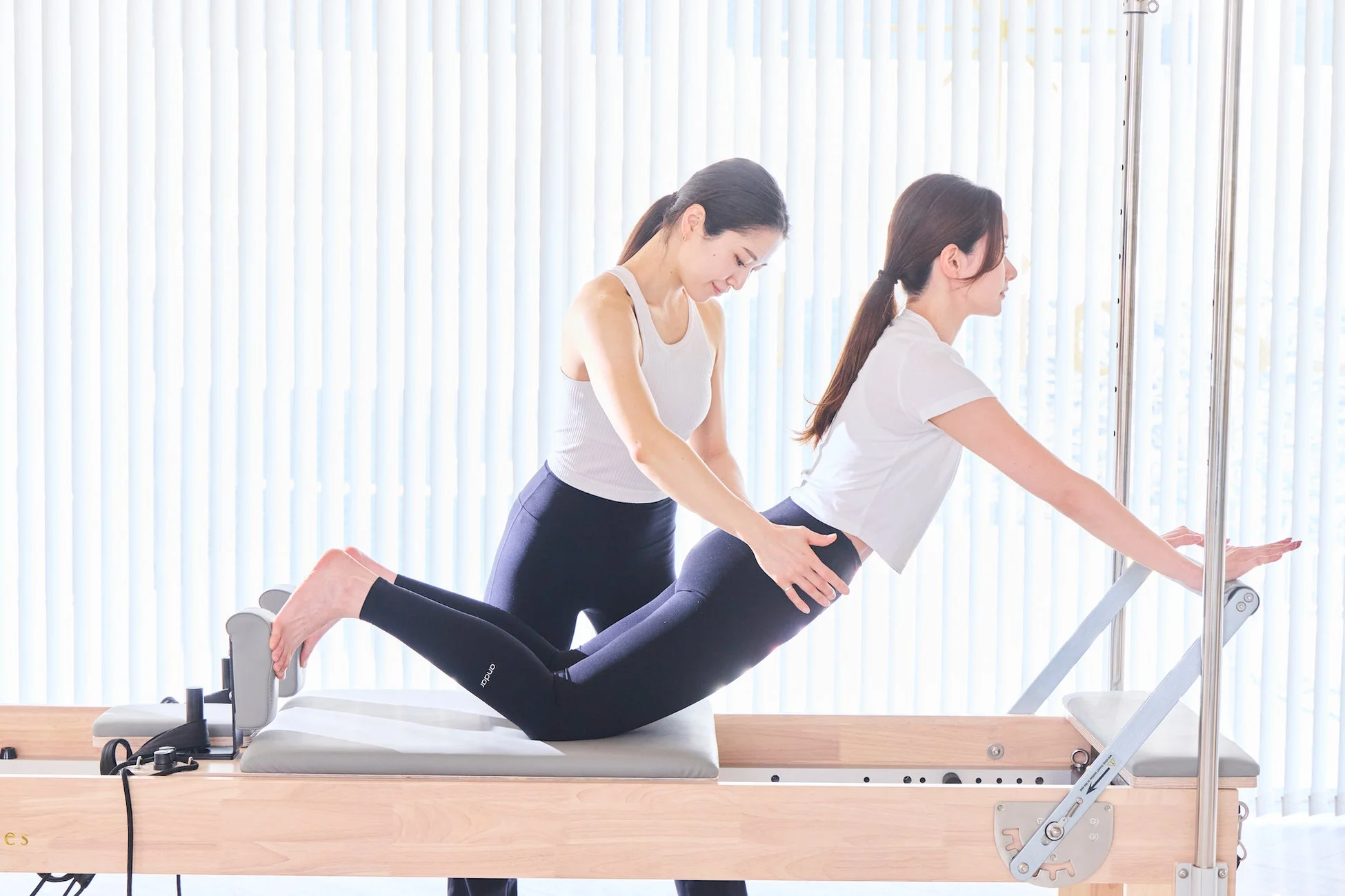 インストラクターが女性のピラティスの動きをサポート