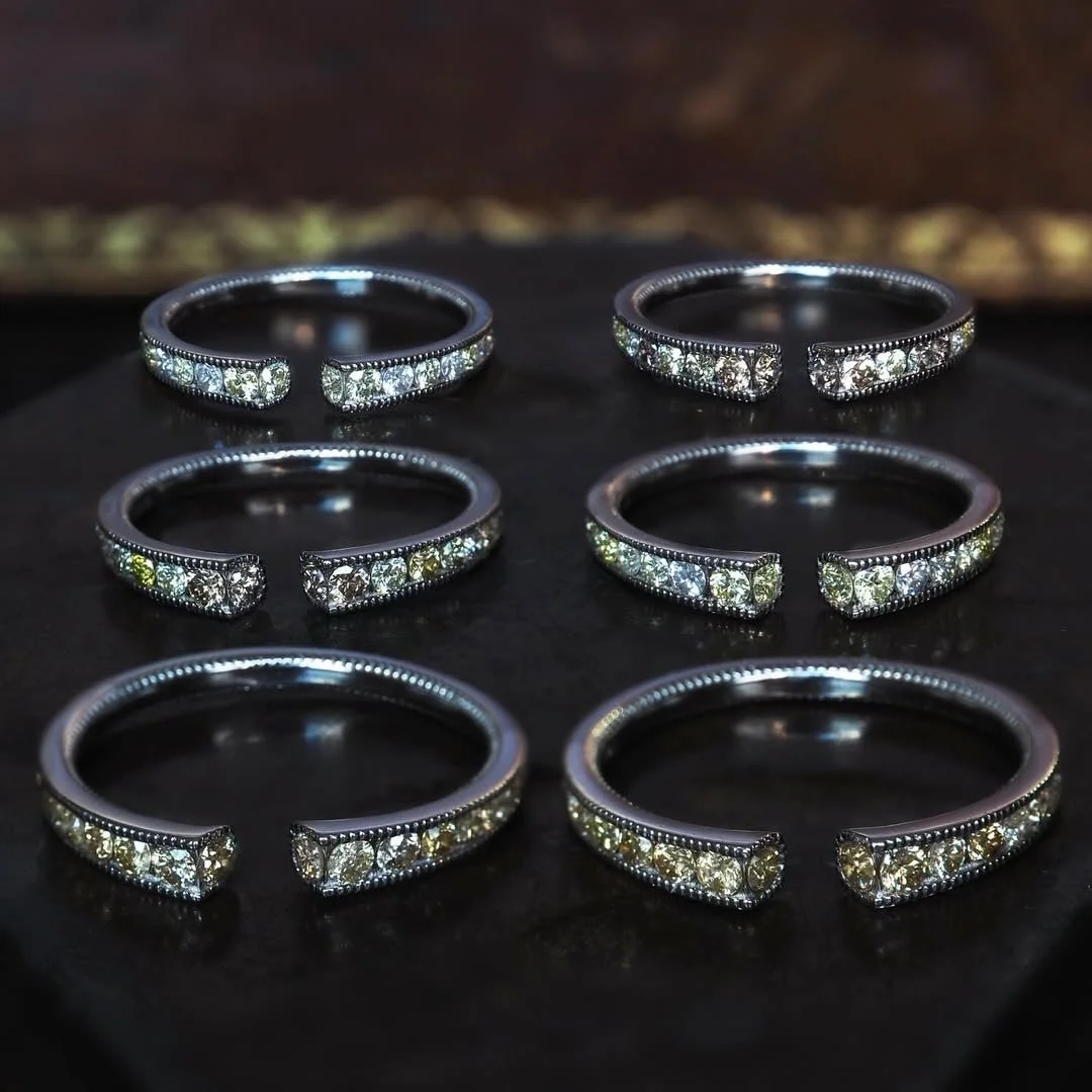 オープンタイプのリングが複数個、暗い背景に並べられています