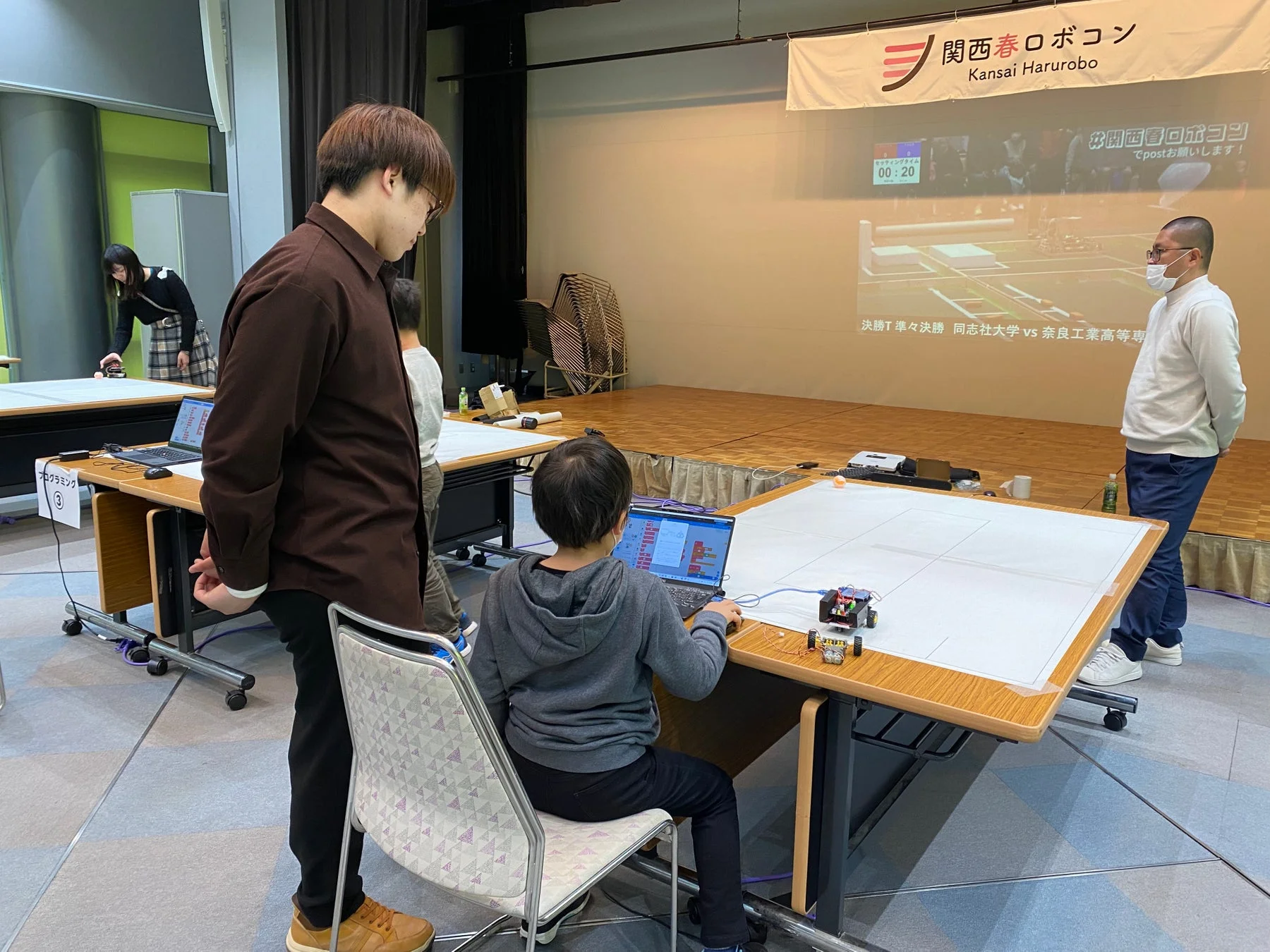 子供がノートパソコンを使って小型ロボットをプログラミングしている様子