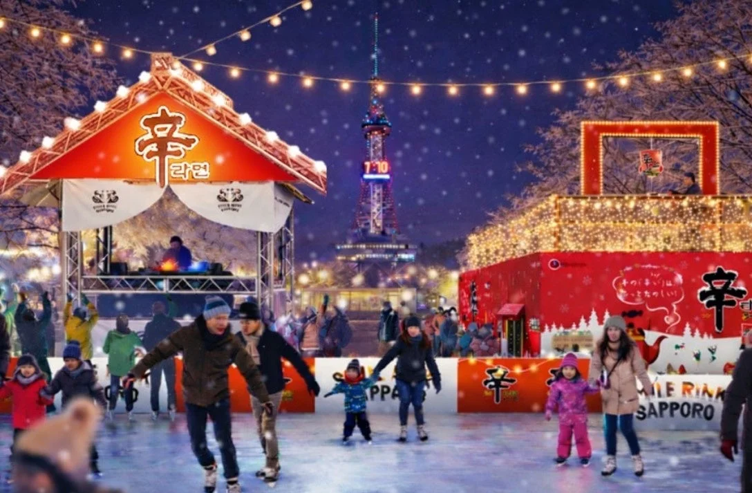 雪が降る冬の夜、札幌テレビ塔が見える屋外アイススケートリンクで、多くの人々がスケートを楽しんでいます。