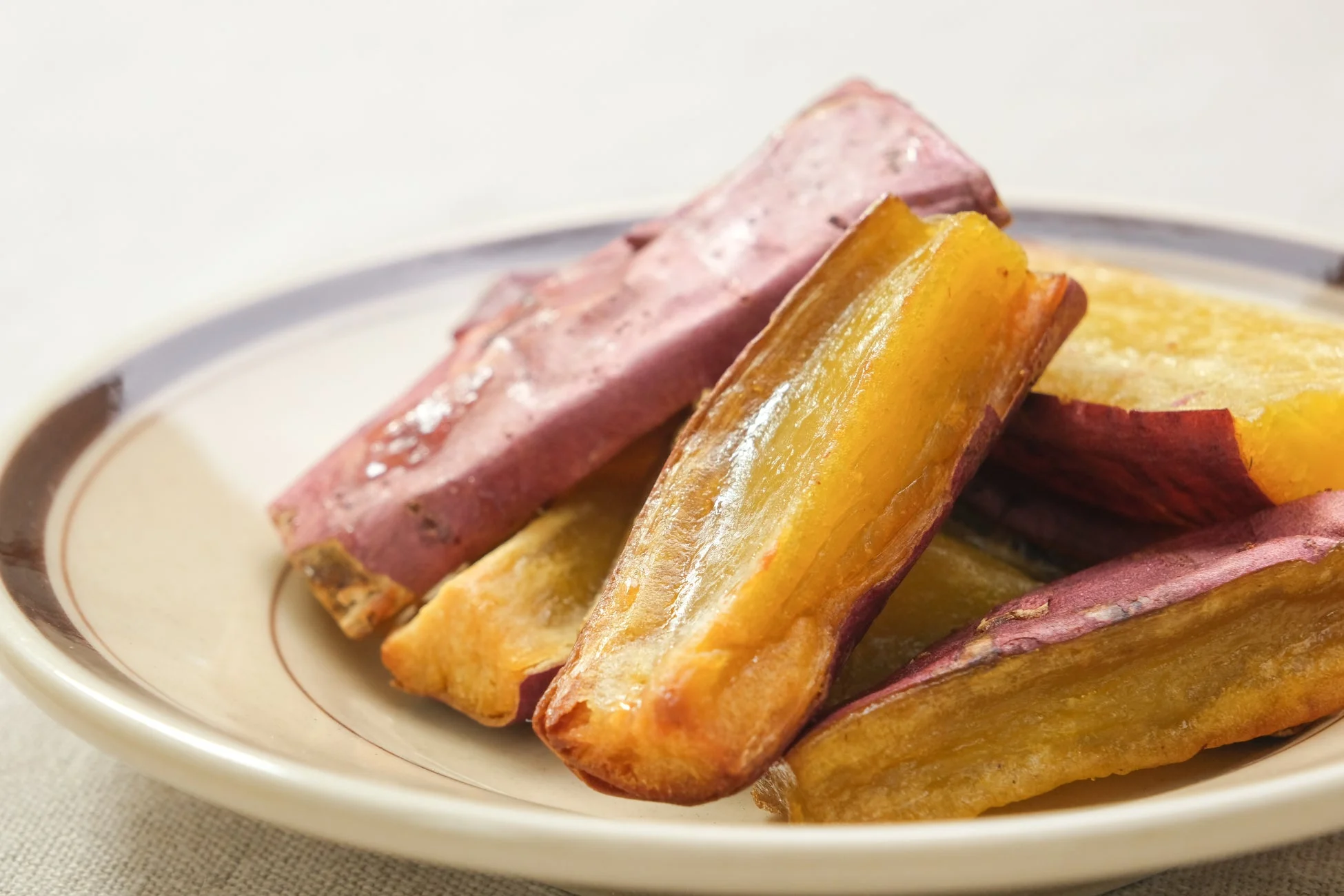 皮付きのさつまいもが、黄金色に焼かれて（または揚げられて）お皿に盛り付けられています。甘く香ばしい秋の味覚を感じさせる、食欲をそそる一品です。