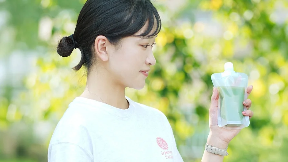 屋外でパウチドリンクを持つ女性