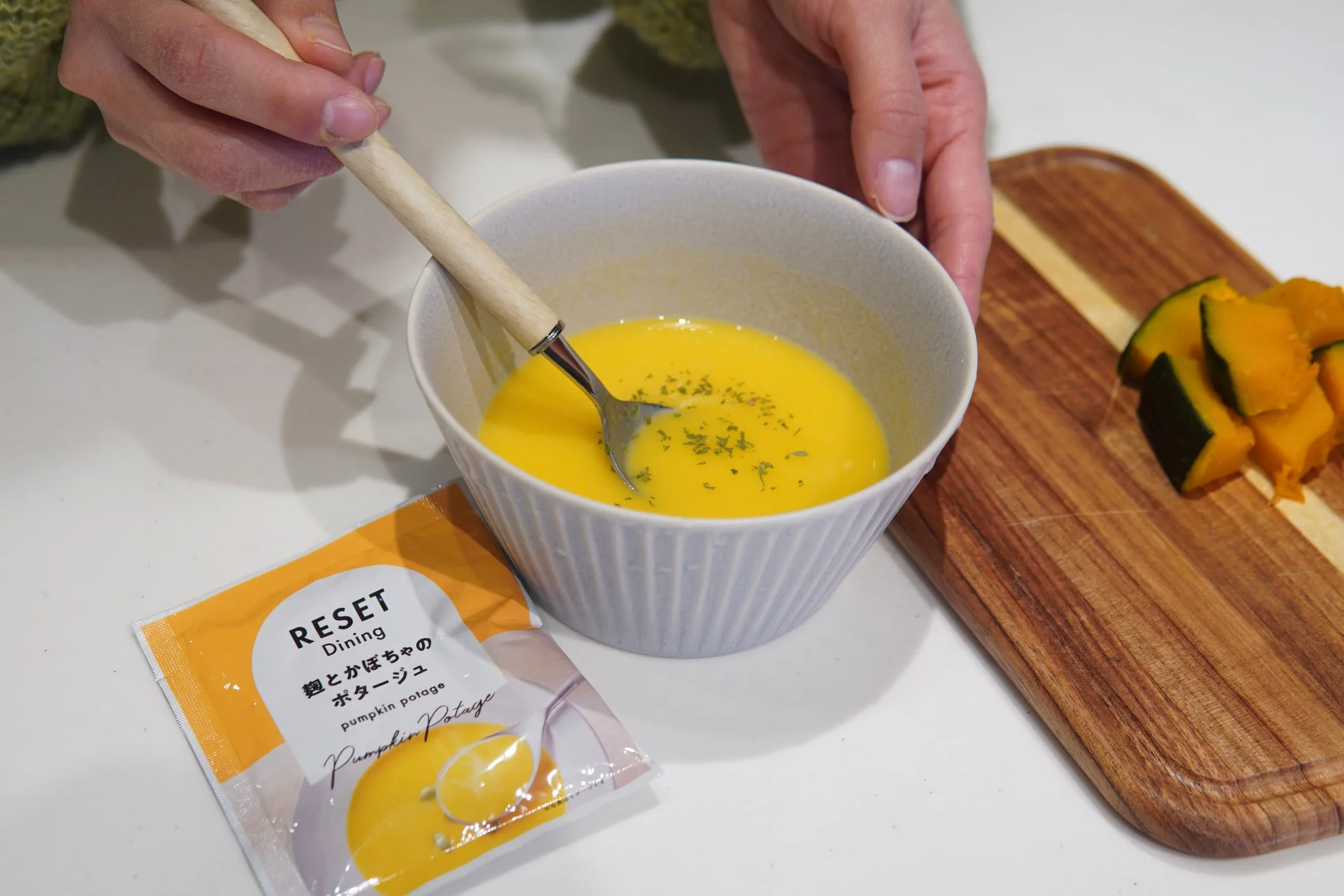 スプーンでかぼちゃのポタージュを混ぜる手元