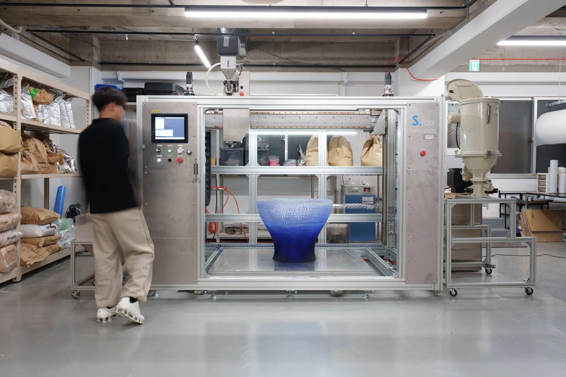 大型3Dプリンターと、青いグラデーションが美しい造形物