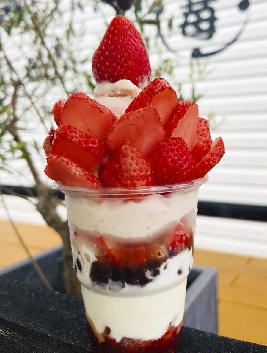 大量の新鮮ないちごがたっぷり盛り付けられた、層になったクリームといちごソースが美しいパフェ