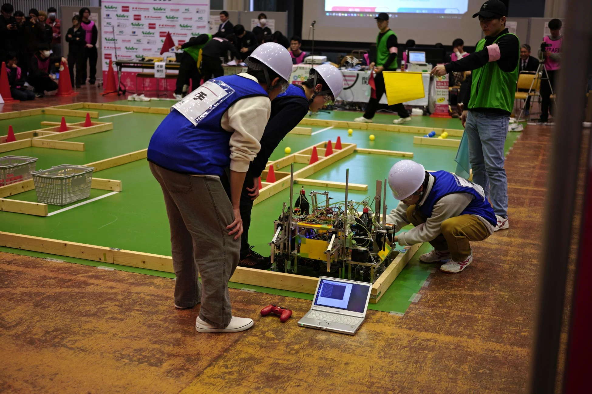 ロボット競技会でロボットを調整する学生たち